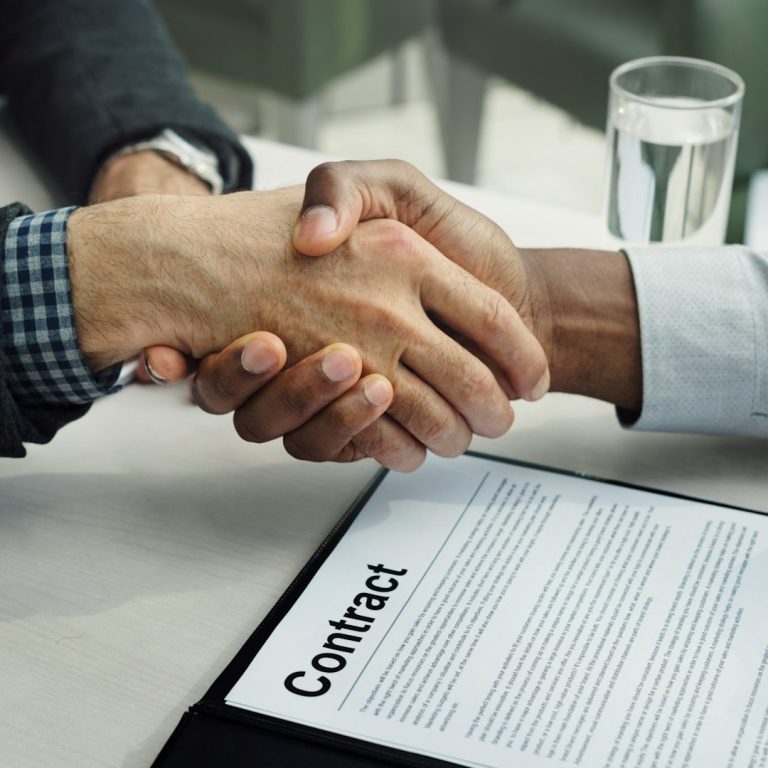 Handshake over a contract document on a table.